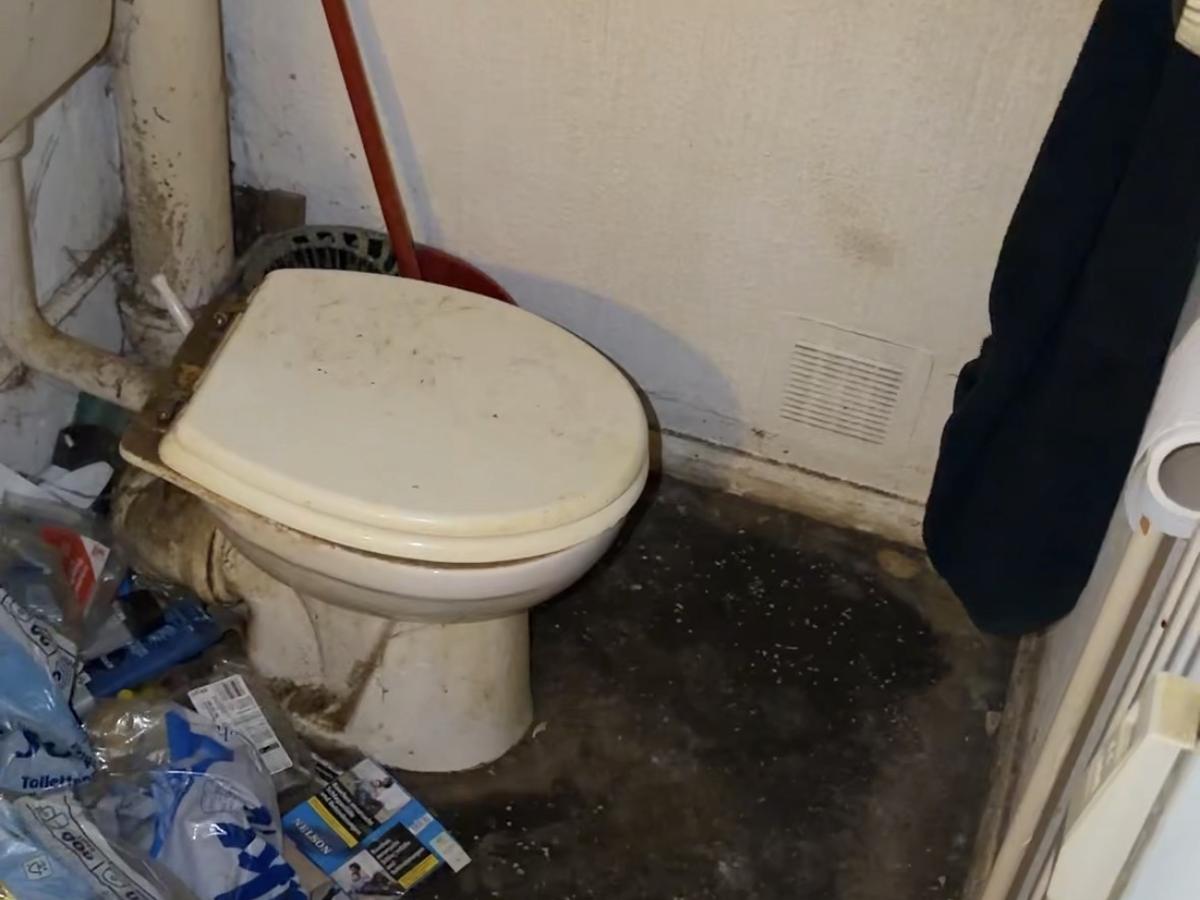 Verschmutztes Badezimmer vor der Räumung mit Müll auf dem Boden